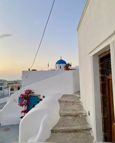 stairs leading up to a building with a blue dome on the top and white walls