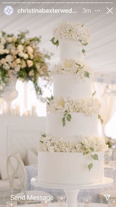 a wedding cake with white flowers on top is sitting on a table in a tent