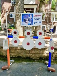 several pieces of art on display in front of a tree and sign that says sharpen target practice