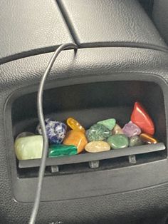 the interior of a car with colorful rocks and stones in the center console compartment, plugged into a charger