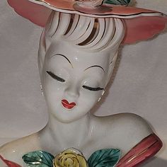 a ceramic figurine wearing a pink hat with flowers on it's head