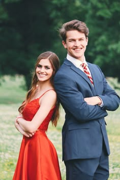 a man in a suit and tie standing next to a woman in a red dress