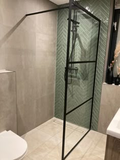 a glass shower door in a bathroom next to a toilet