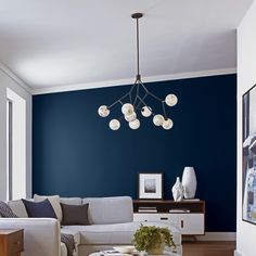 a living room with blue walls and white furniture in the center, along with a coffee table