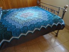 a bed with a blue blanket on top of it next to a wooden headboard