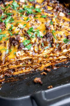 a cheesy casserole dish with meat and cheese on top, in a black pan