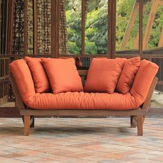 an orange couch sitting on top of a brick floor next to a wooden frame wall