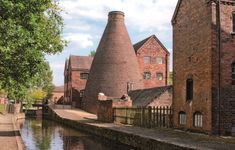 an old brick building next to a river with water running between it's sides