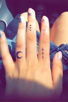 two fingers with different tattoos on them, one has an arrow and the other has a crescent