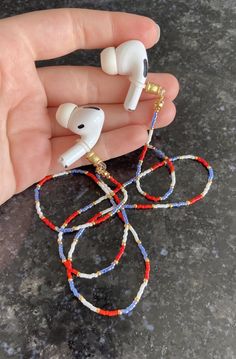 a hand is holding two ear buds that are made out of beads