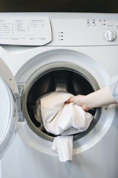 a person holding a napkin in front of a washing machine