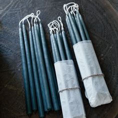 four black candles wrapped in white paper and tied with twine on top of a plate