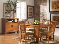 a dining room table and chairs in front of a brick wall with pictures on it