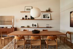 a dining room table with chairs and pictures on the wall above it, along with an area rug