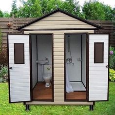 an outdoor toilet in the middle of a yard with two doors open to reveal it's outside