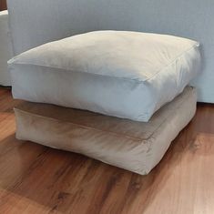 two pillows stacked on top of each other in the middle of a room with wood floors