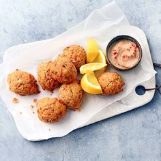 some food is sitting on a white tray with lemon wedges and ketchup