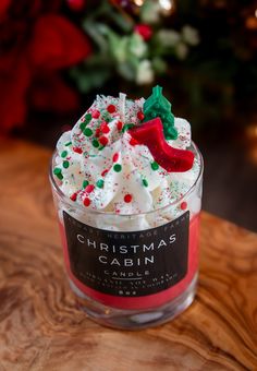 a glass jar filled with whipped cream and sprinkles on top of a wooden table