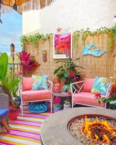 an outdoor living area with colorful furniture and plants on the wall, including a fire pit