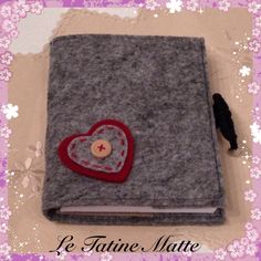 a small gray book with a red heart on it