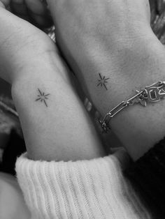 two people holding hands with tattoos on their arms and one is wearing a chain bracelet