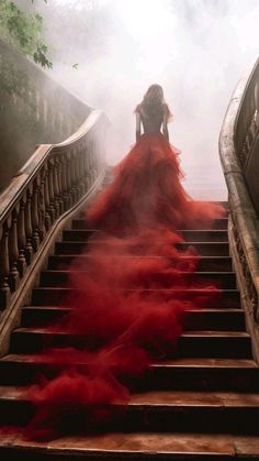 a woman in a long red dress is walking down the stairs with her hands on her hips