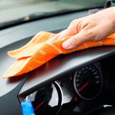 a person cleaning the dashboard of a car with a micro towel and cloth on it