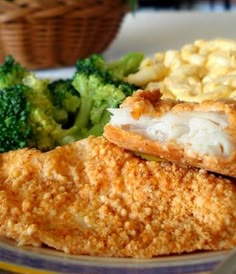 a plate with chicken, broccoli and macaroni on it next to a basket