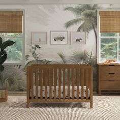 a baby's room with tropical wallpaper and wooden crib in the foreground