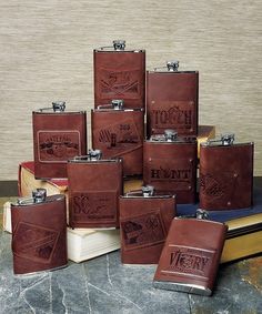 six leather flasks are stacked on top of each other in front of a stack of books