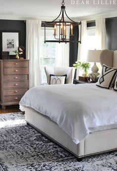 a bedroom with black walls, white bedding and a chandelier hanging from the ceiling