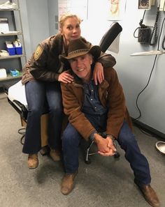 a man sitting on the back of a chair next to a woman in a room