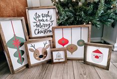 four framed christmas ornaments are sitting on the floor in front of a christmas tree and other holiday decorations