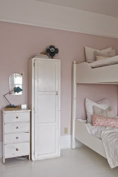 a bedroom with pink walls and white furniture