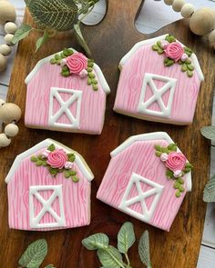 three decorated cookies sitting on top of a wooden cutting board next to leaves and flowers