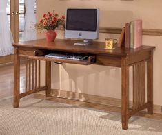 a wooden desk with a computer monitor and keyboard sitting on it's top shelf