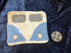 a crocheted blue and white blanket next to a button on a black jacket