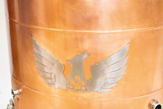 a large metal barrel with two silver birds on it's front and back sides