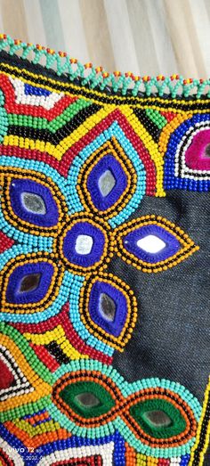 a close up of a colorful beaded bag on a wooden floor with stripes in the background