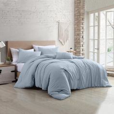 a bed with blue comforter and pillows in a room next to a brick wall