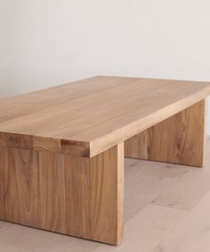 a wooden bench sitting on top of a hard wood floor next to a white wall