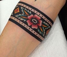 a woman's arm with a tattoo on it that has flowers and leaves painted on it