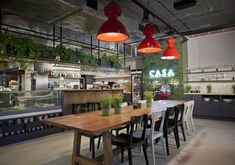 a restaurant with tables, chairs and plants in the center is lit by hanging lights