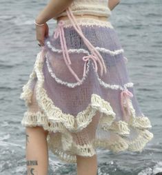 a woman standing on top of a rock next to the ocean wearing a purple dress