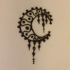 a metal clock that is hanging on the wall in front of a white wall with black beads