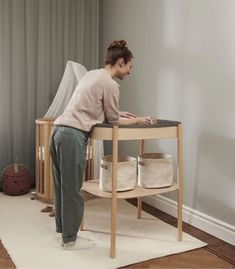 a woman standing on top of a wooden table next to a white rug and window