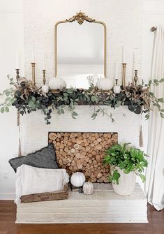 a white fireplace with greenery and candles