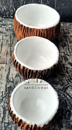 three white bowls with brown rims sitting on top of a stone table next to each other