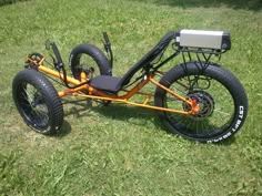 an orange and black motorized bike sitting in the grass