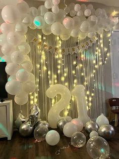 balloons and streamers are on the floor in front of a number twenty balloon arch